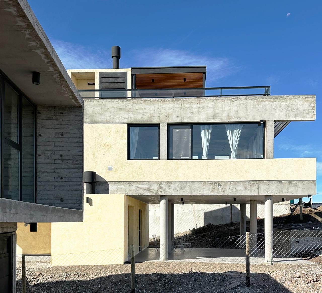 Esquina de la casa: el volumen de hormigón visto apoyado sobre pilotes cilíndricos, fotografía de obra