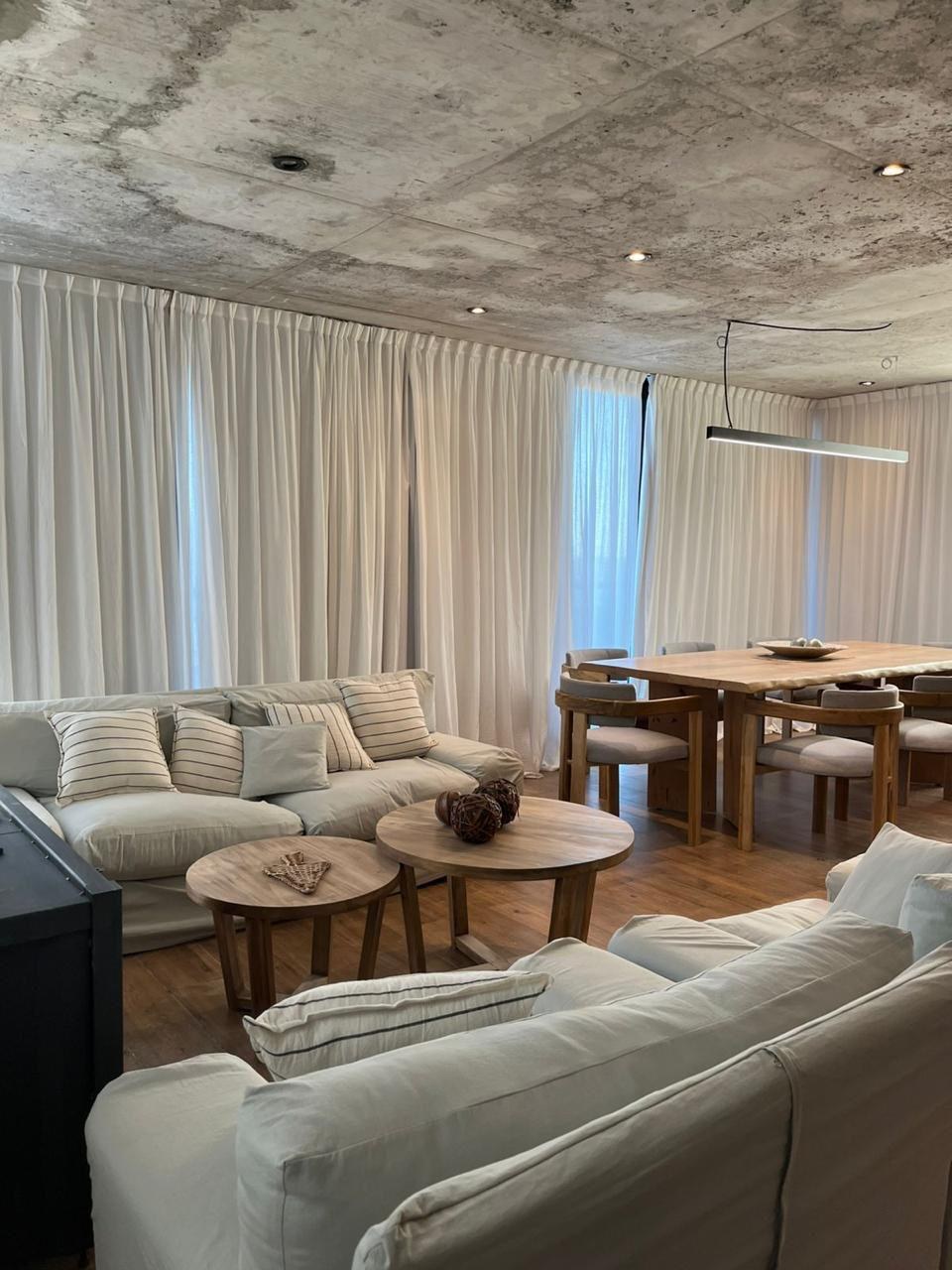 Estar con sillones claros y mesas bajas de madera, fotografía de obra